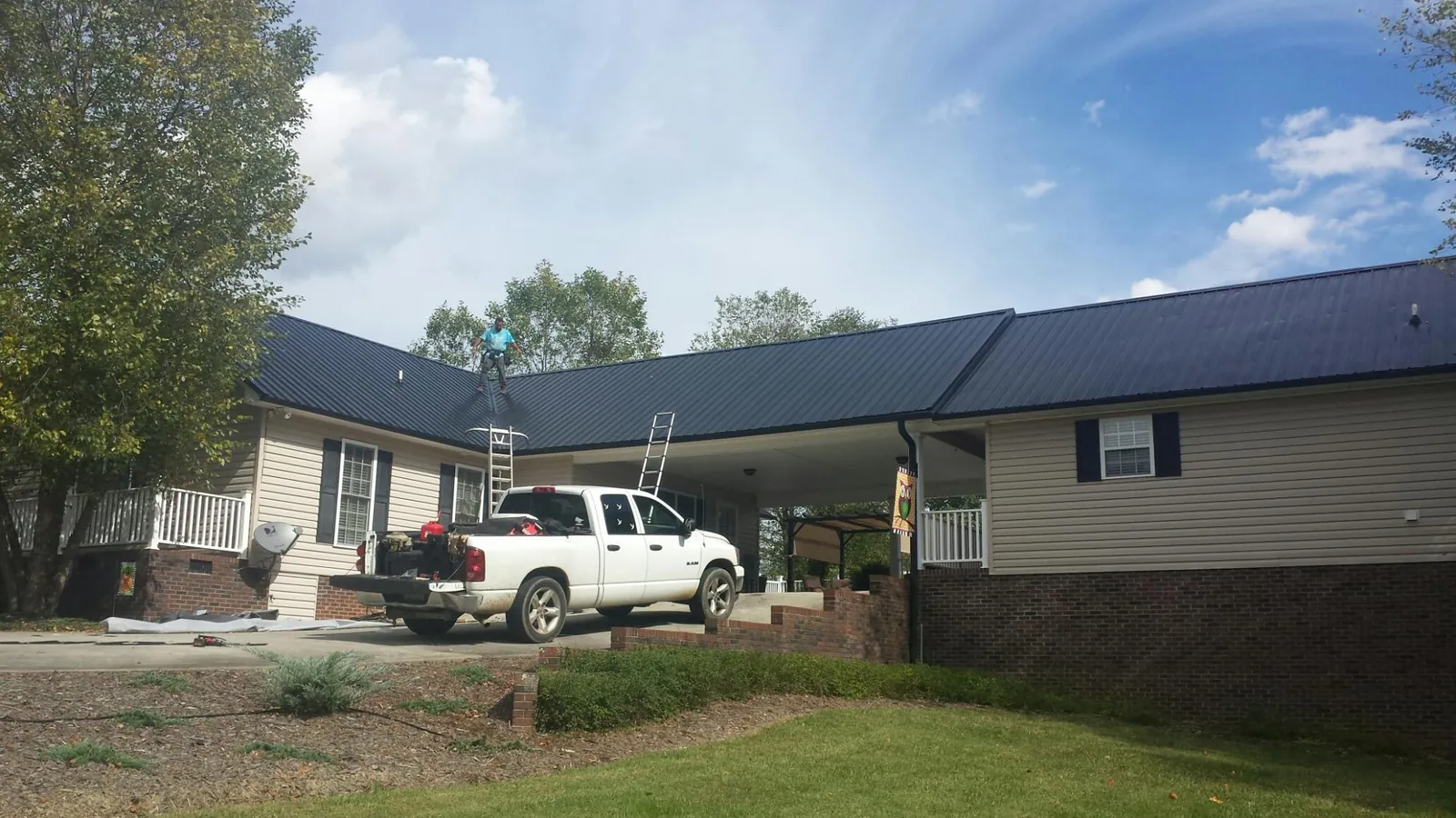 Black metal roof over a home and attached breezeway with ladders set in Jamestown